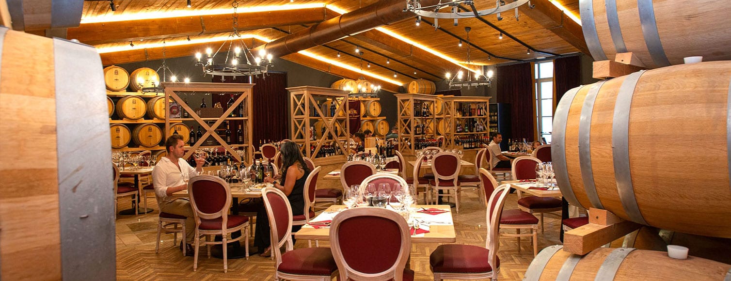 cantina-hotel-eventi La sala della cantina con i tavoli apparecchiati e le botti di rovere.