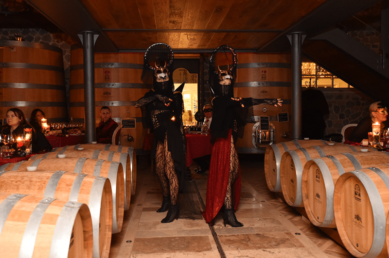 Due figuranti in costume fra le botti, durante una serata in maschera in cantina.
