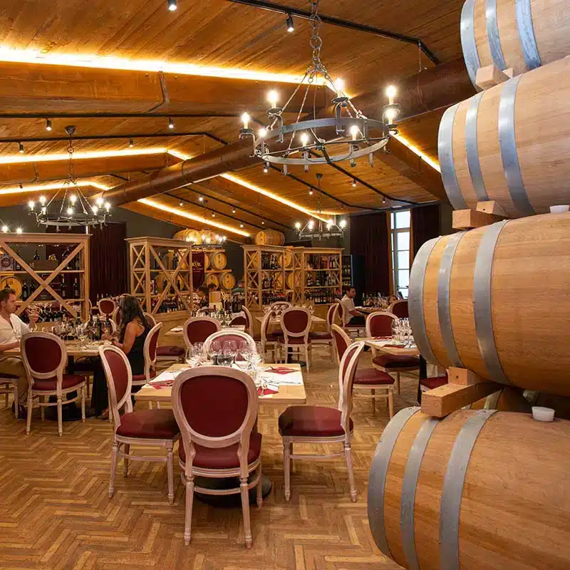 La sala della cantina con i tavoli apparecchiati, le botti e i lampadari di ferro.